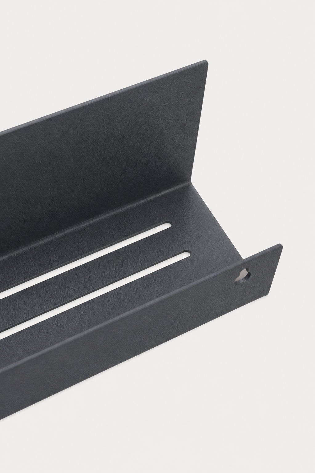 METI bathroom shelf in Slate powder coated steel, RAL 7016, angled close-up of the slotted drainage tray, keyhole mount visible