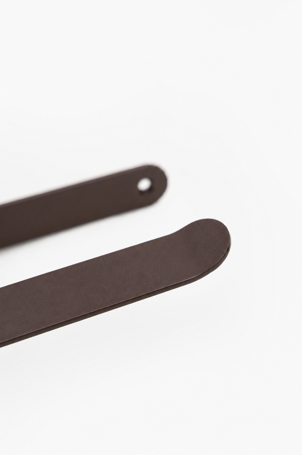 CLAIR toilet paper holder in Umber powder coated steel, RAL 8022, macro of the sweeping arm and rounded plate, dark black brown