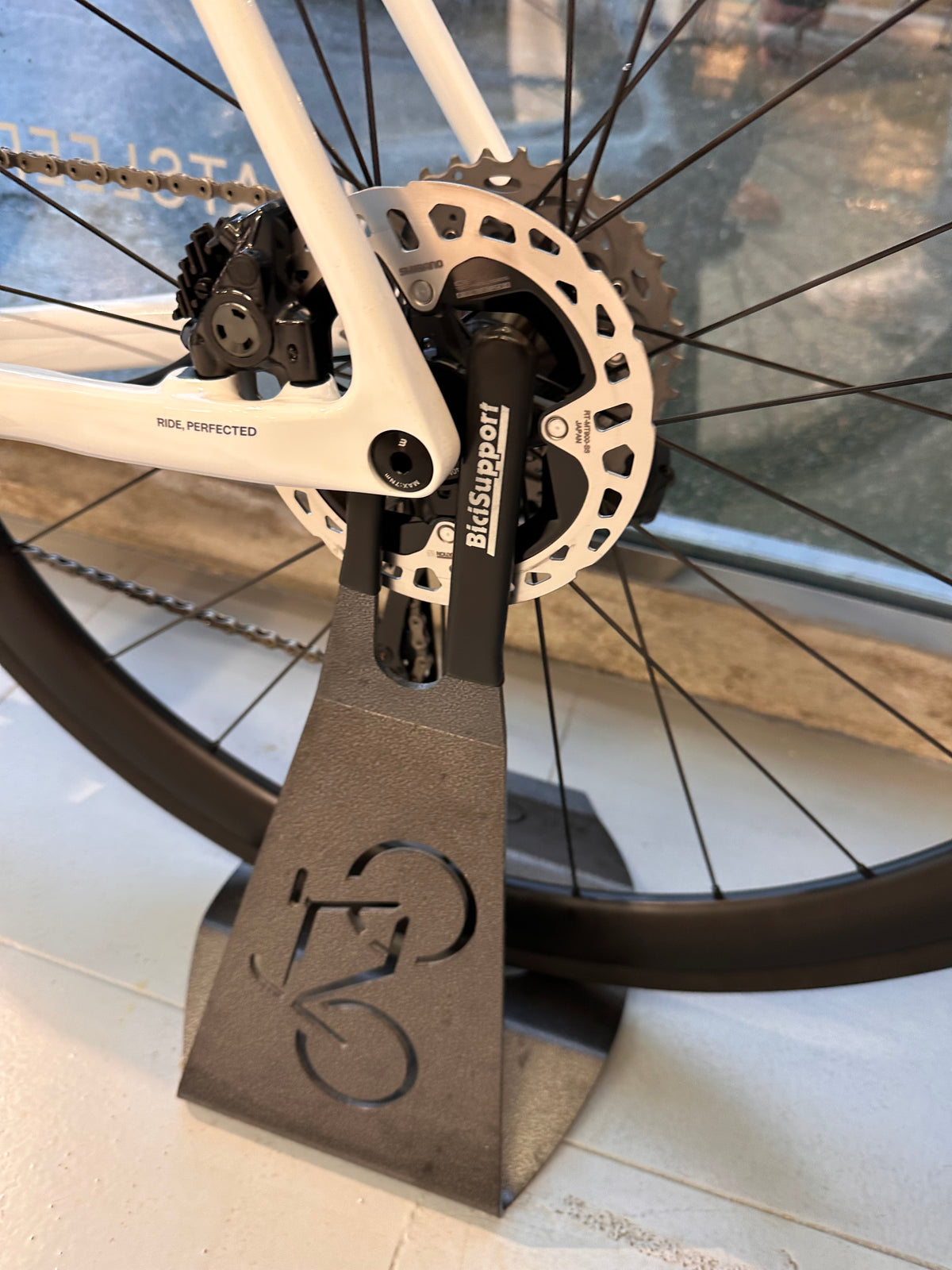 A custom powder coated steel bike stand with a cut-out cyclist motif, built by ATYP, holding a road bike.