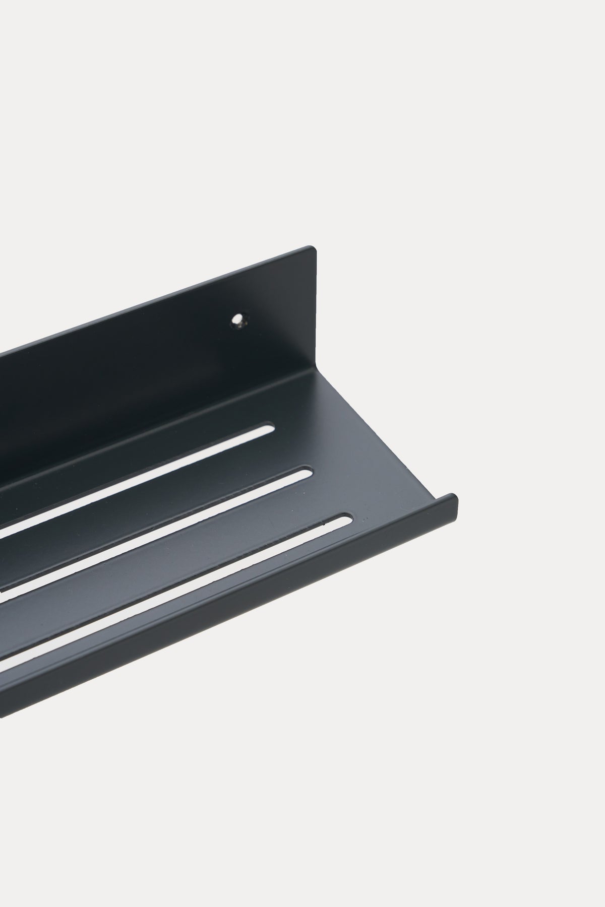 ELIORA shower shelf in powder coated steel, close-up of the slotted tray and front lip, jet black