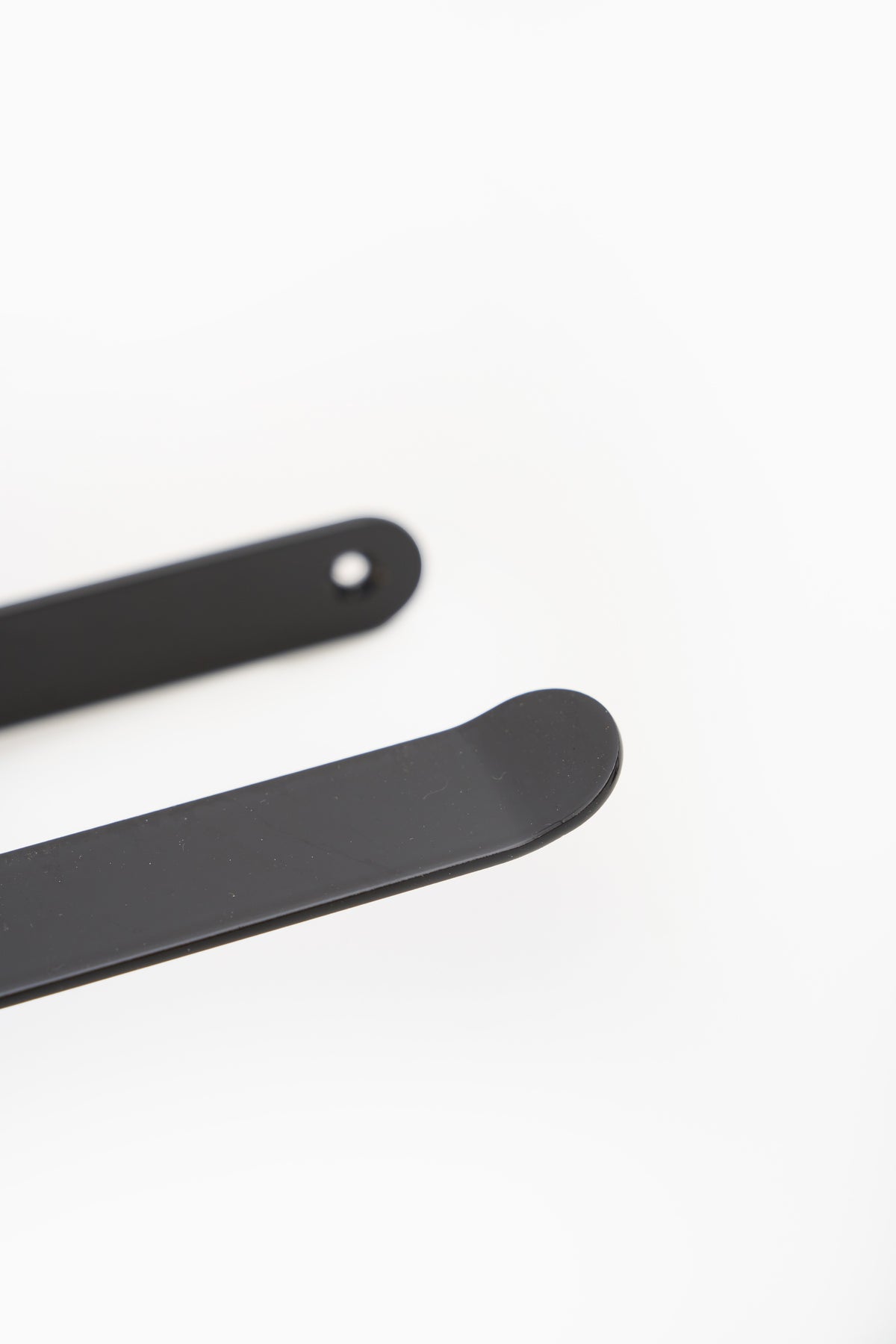 CLAIR toilet paper holder in powder coated steel, close macro along the black arm toward the rounded plate
