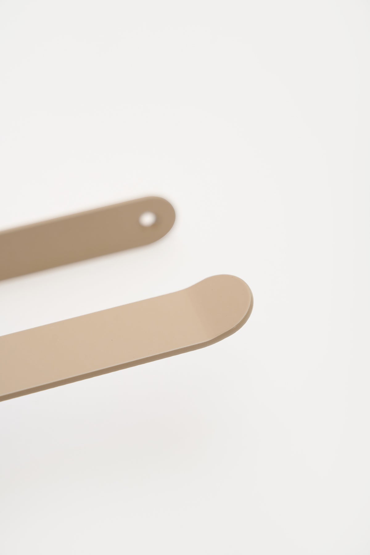 CLAIR toilet paper holder in Linen powder coated steel, macro of the sweeping arm and rounded plate, warm beige