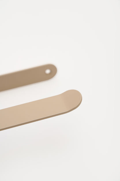 CLAIR toilet paper holder in Linen powder coated steel, macro of the sweeping arm and rounded plate, warm beige