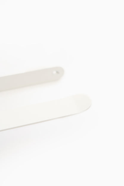 CLAIR toilet paper holder in Chalk powder coated steel, macro of the white arm and rounded plate, arm tip in focus