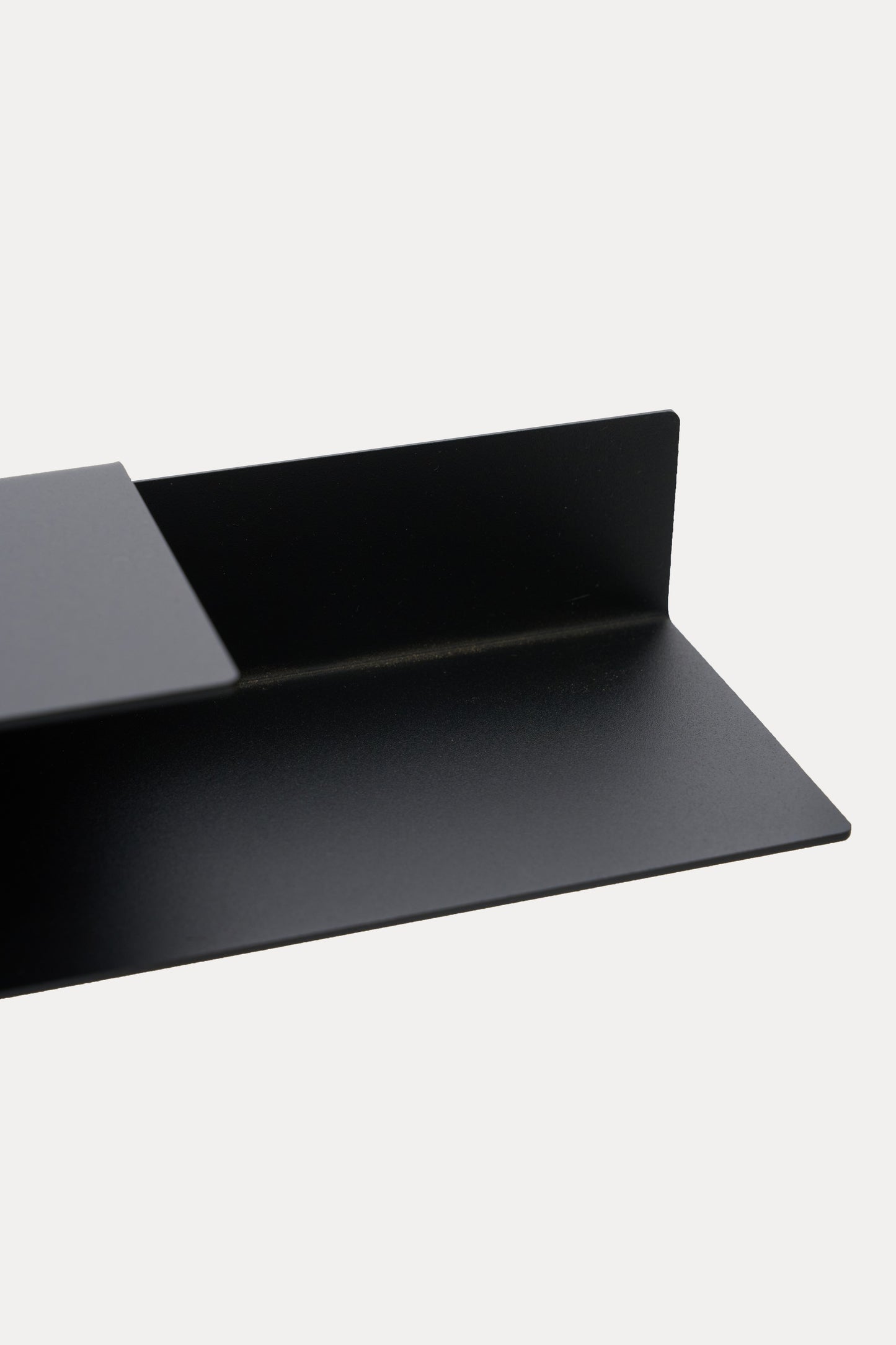 NYVE toilet paper holder in powder coated steel, wide close-up of the shelf and hook arm with roll slot, deep black with a soft sheen