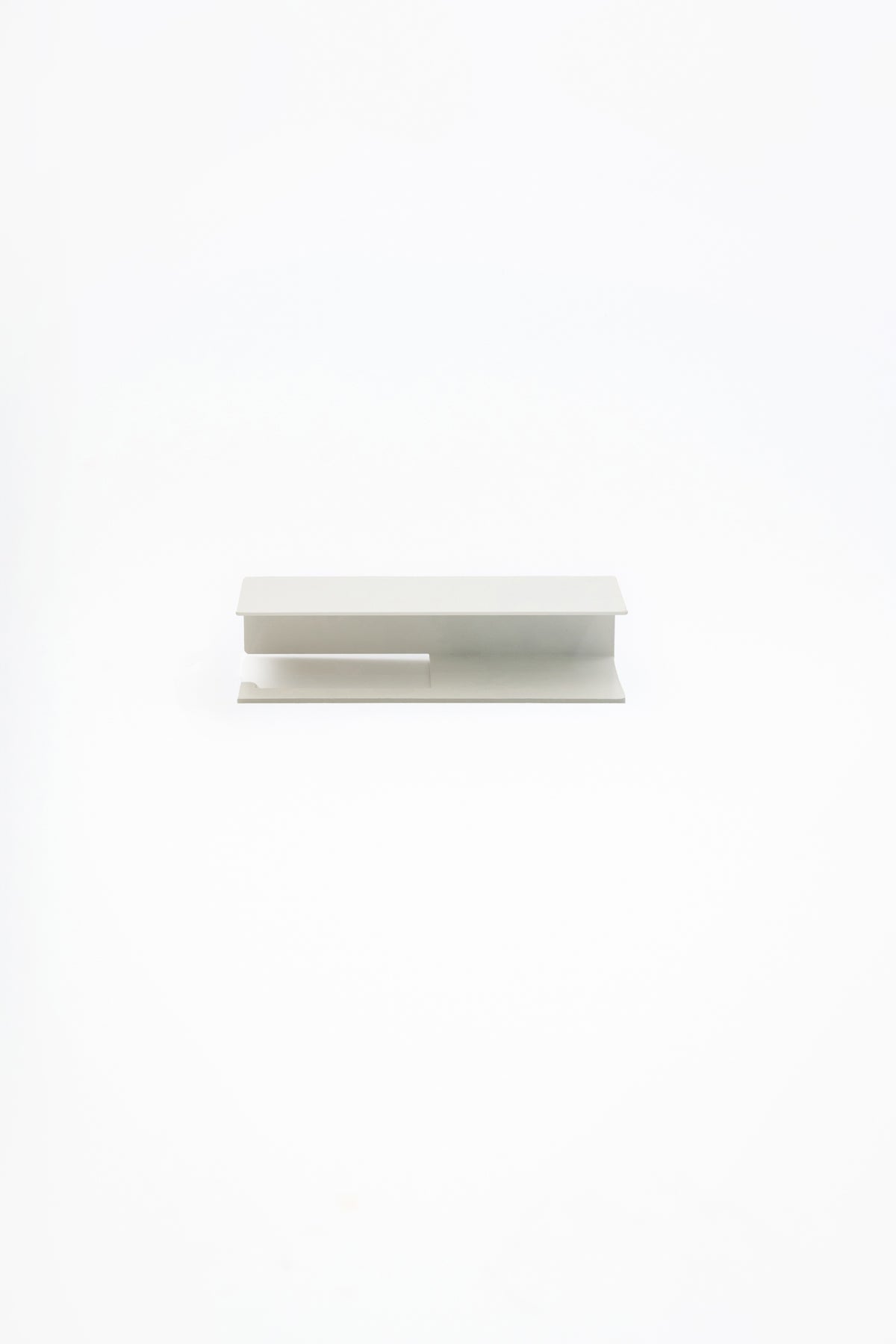 NYVE toilet paper holder in powder coated steel, full front view of the compact holder in a soft pale finish