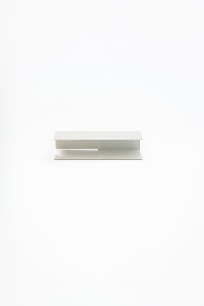 NYVE toilet paper holder in powder coated steel, full front view of the compact holder in a soft pale finish